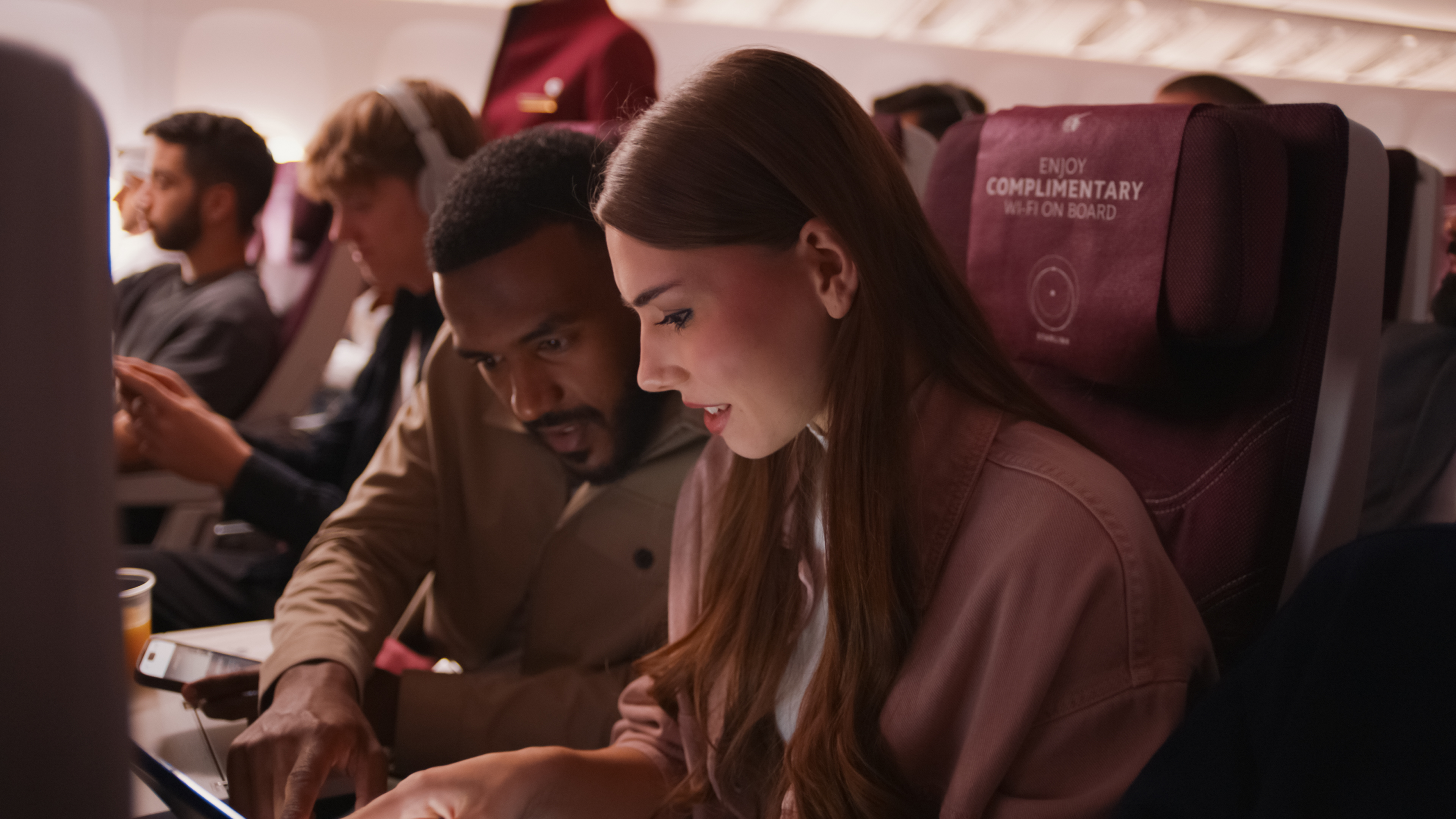A man and woman on a plane looking down at a screen