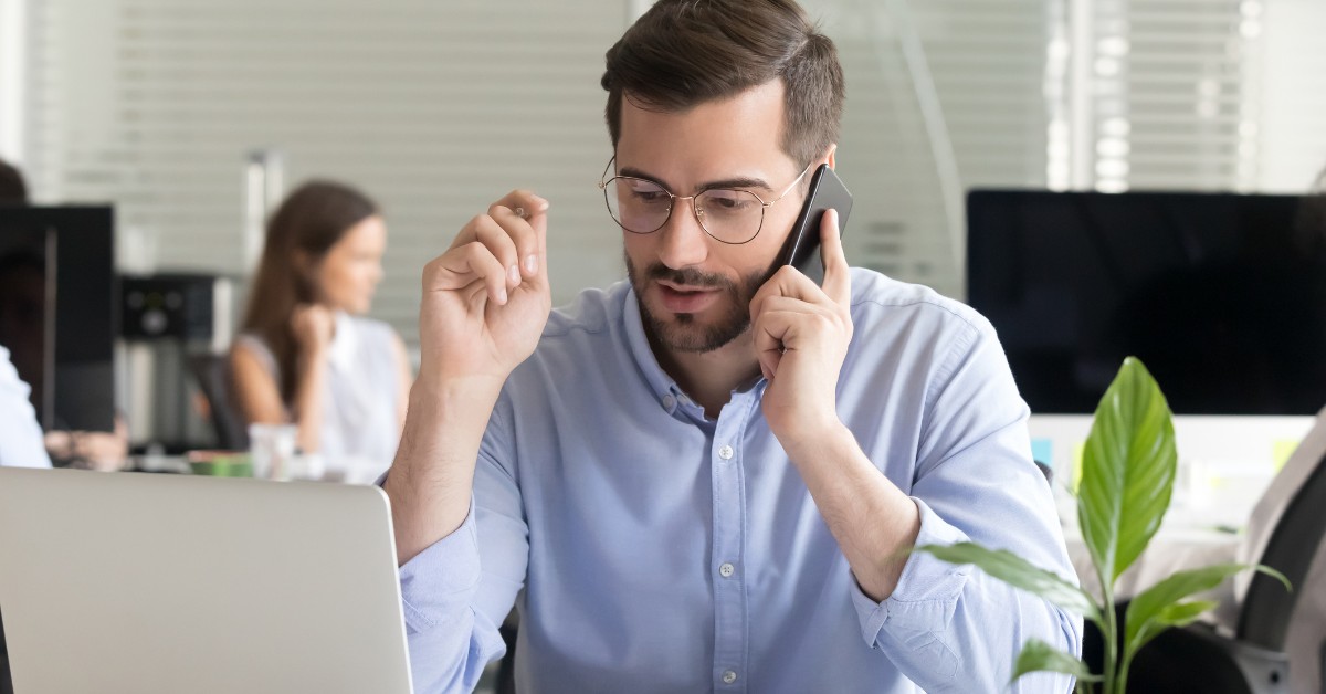A man in an office talking on a mobile phone