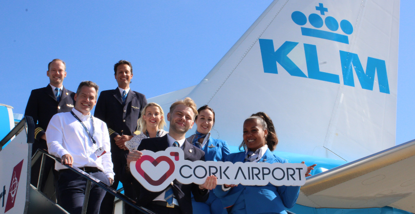 People posing with a sign outside an airplane