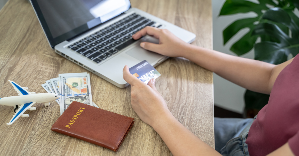 A closeup of a person holding a credit card and typing on a laptop