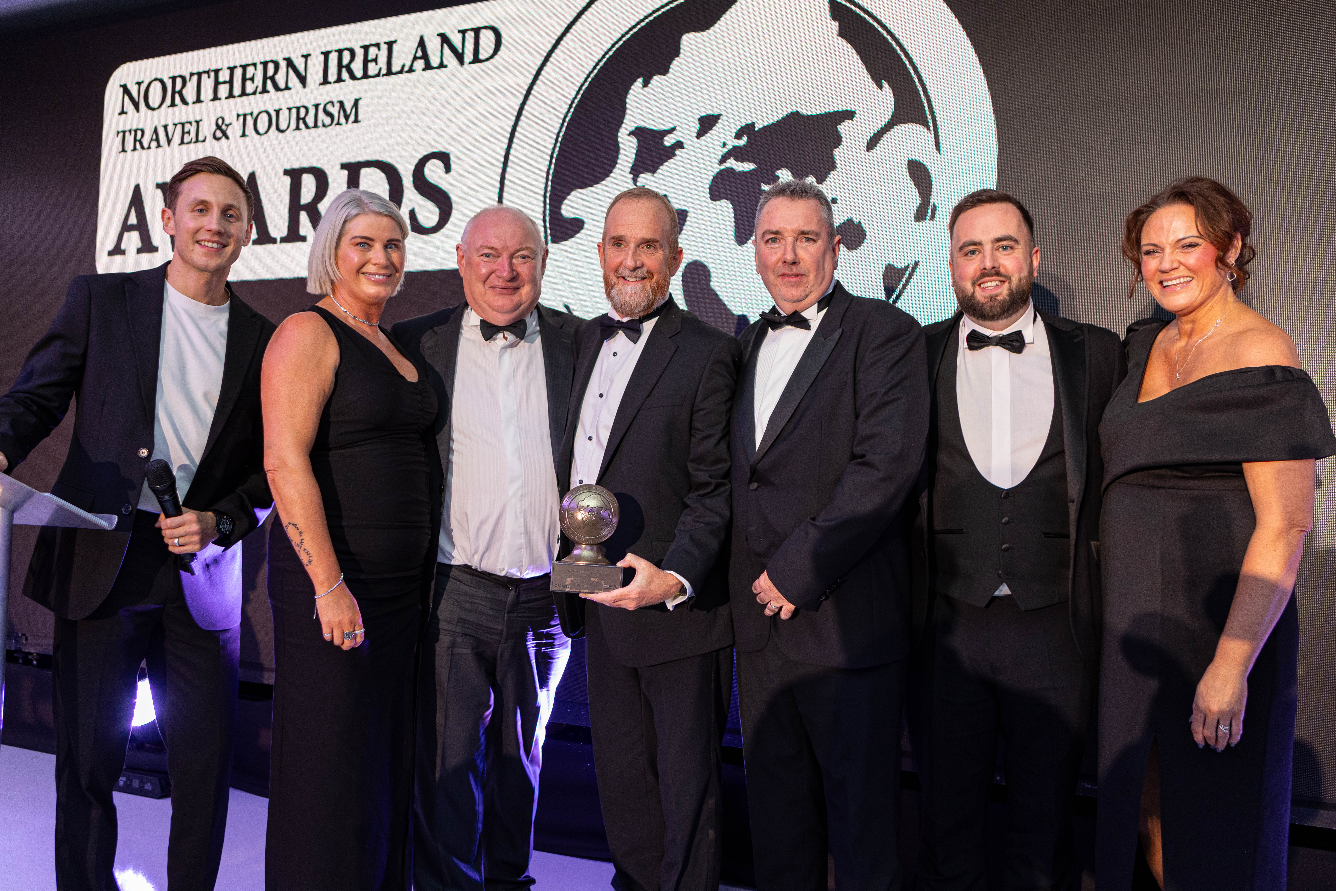 A group of people in formal wear smiling and holding an award