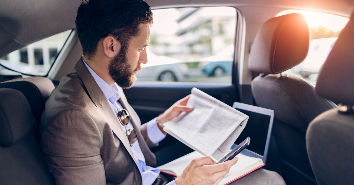 A man looking over a newspaper in a car