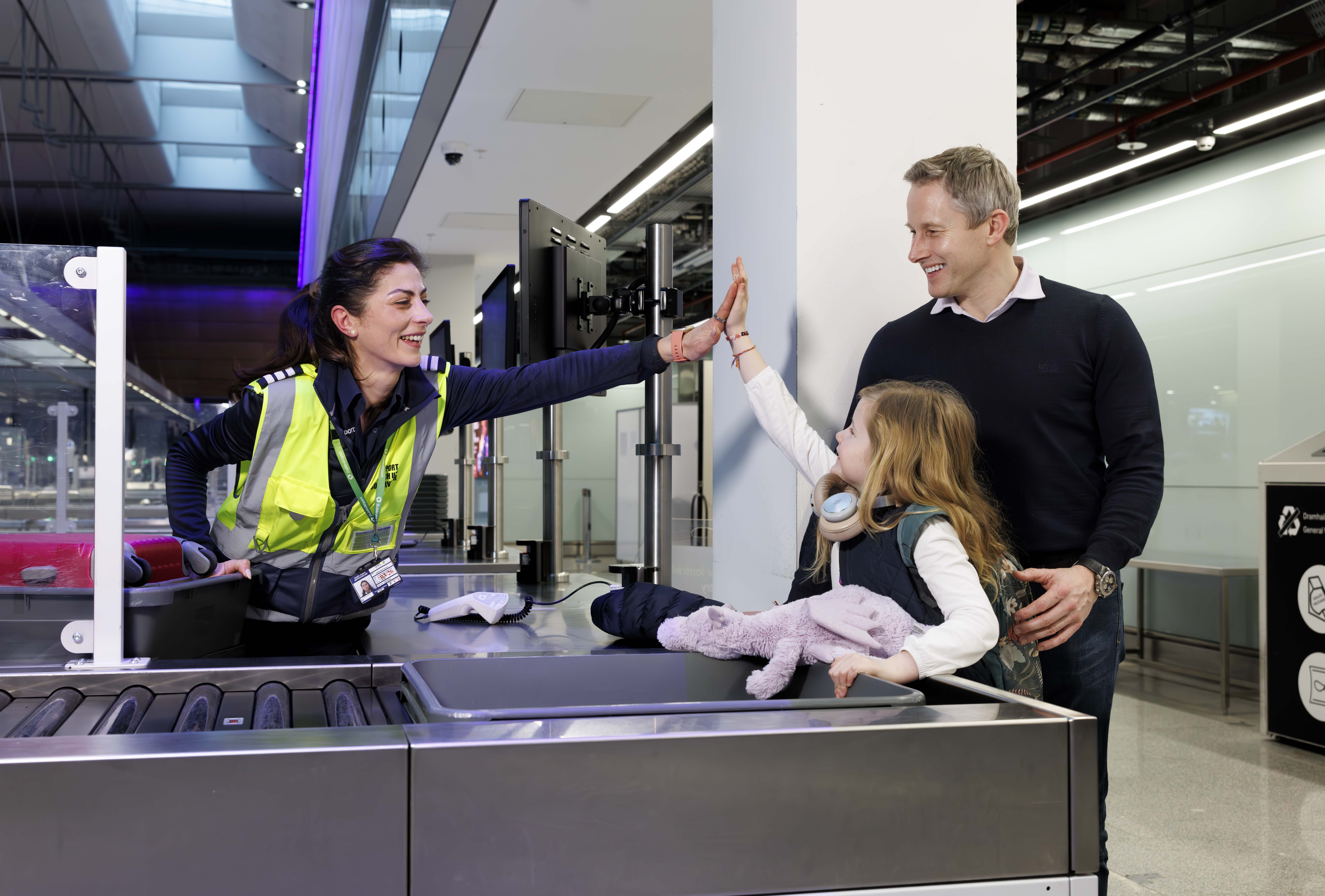 A woman high fiving a child at airport security scanners