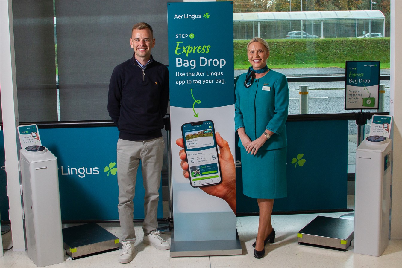 Two people smiling beside a banner sign