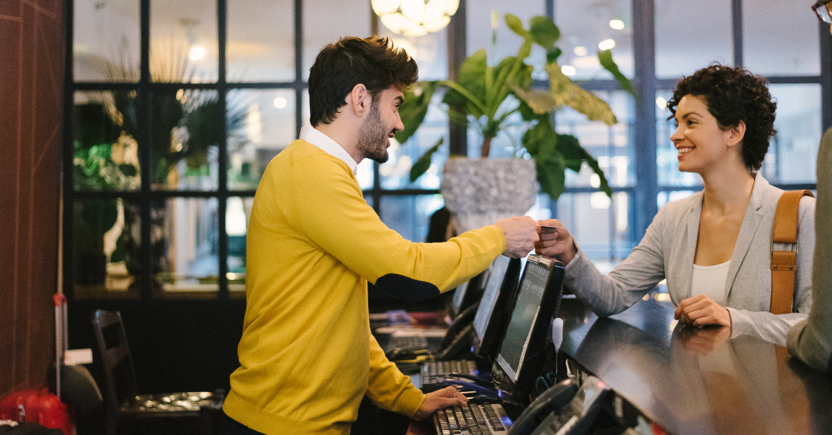 A man at reception handing a credit card to a woman