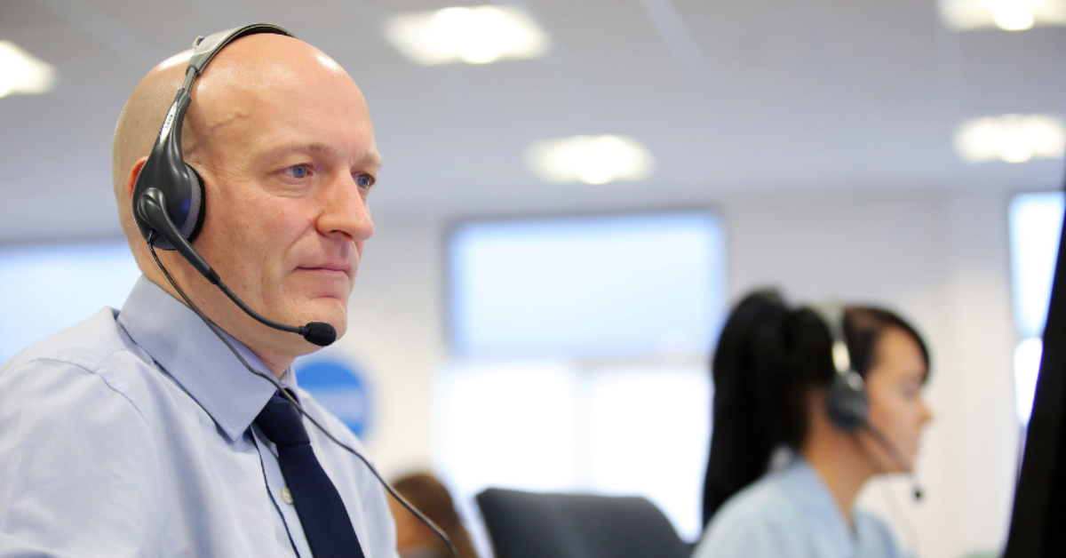 A man wearing a headset looking at a computer screen