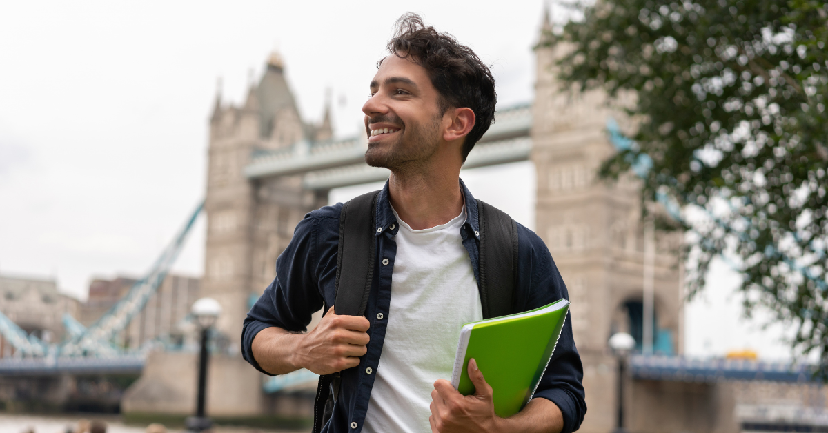 A student smiling and walking in front of Tower Bridge