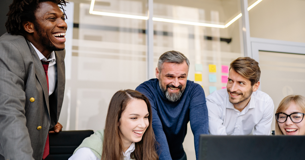 A group of people smiling at a computer screen