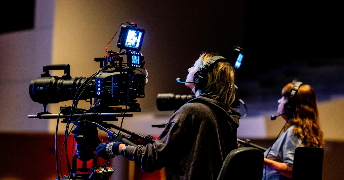 A woman standing behind a film camera