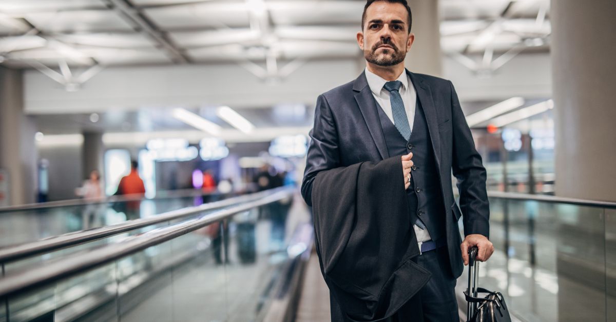 Man wearing a suite carrying a luggage at the airport