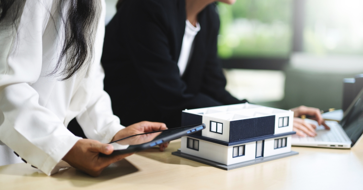 A woman holding a tablet device beside a 3D home model