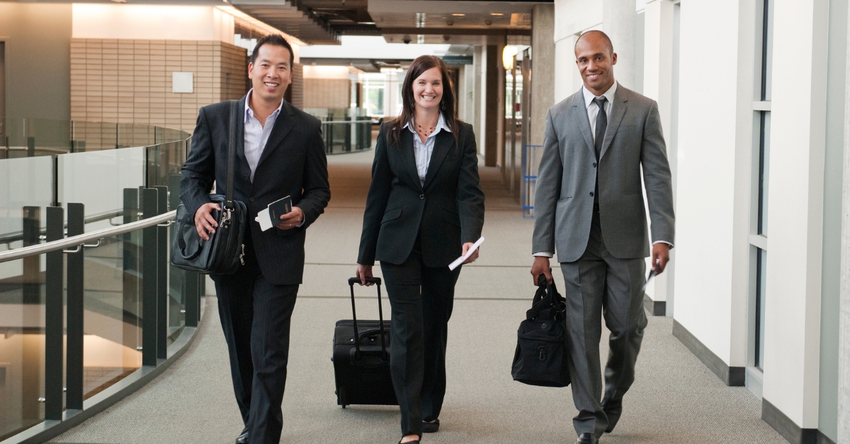 A group of people in corporate wear walking with luggage