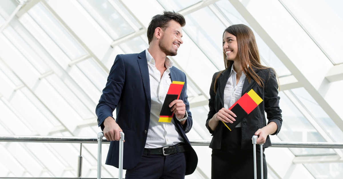 Two people holding travel documents smiling at each other